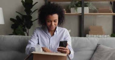 Afrikalı kadın paket kutusunu açıyor. Sipariş edilmiş mallar tatmin oluyor.