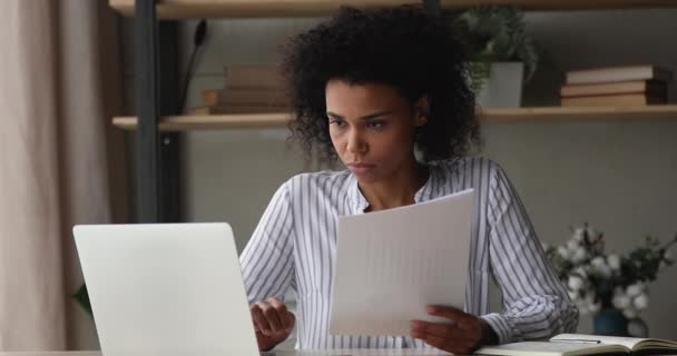 Wanita Afrika yang duduk di meja kerja memegang dokumen belajar informasi — Stok Video