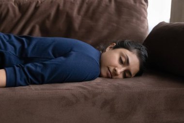 Çok yorgun bir Hintli kadın kanepede uyuyakalıyor.