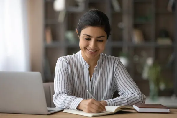 Gros plan femme indienne souriante prendre des notes, étudier à la maison — Photo