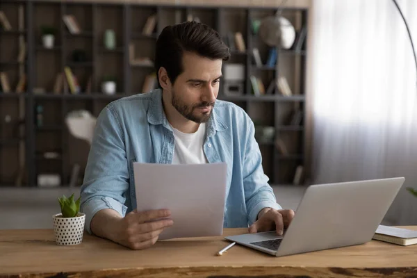 Homem de negócios focado usando laptop, trabalhando com documentos financeiros, projeto de pesquisa — Fotografia de Stock