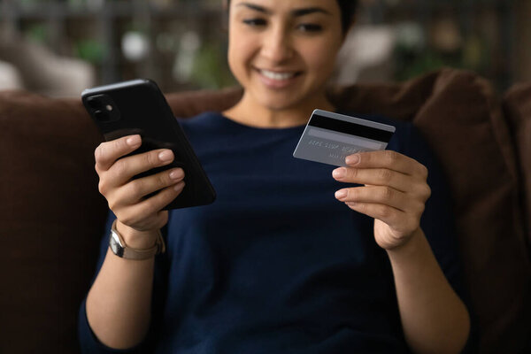 Закрыть счастливую индийскую женщину с помощью смартфона, платить онлайн