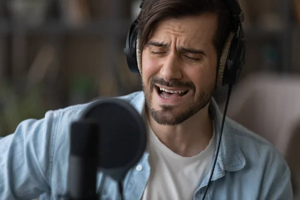 Close up man singer in headphones singing, using professional microphone — Stock Photo, Image