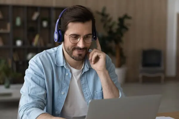 Focused man in headphones and glasses looking at laptop screen — Stock Photo, Image