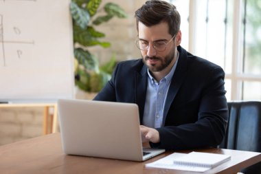 Gözlüklü genç işadamı bilgisayarda çalışıyor..