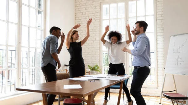 Overjoyed millennial diversificada mista pessoas de negócios de raça dançando no escritório. — Fotografia de Stock