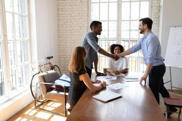 Smiling friendly male leader shaking hands with african american intern. — Stock Photo, Image