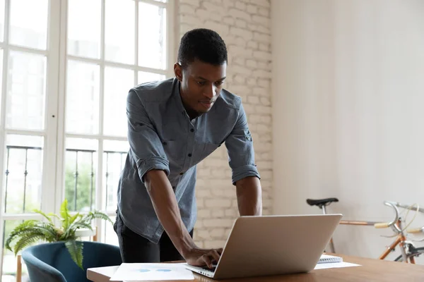 Konzentrierter junger afrikanisch-amerikanischer Geschäftsmann arbeitet am Computer. — Stockfoto