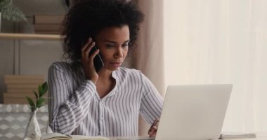 İş kadını cep telefonuyla müşteriyle konuşur, laptop kullanır, anlaşmayı tartışır.