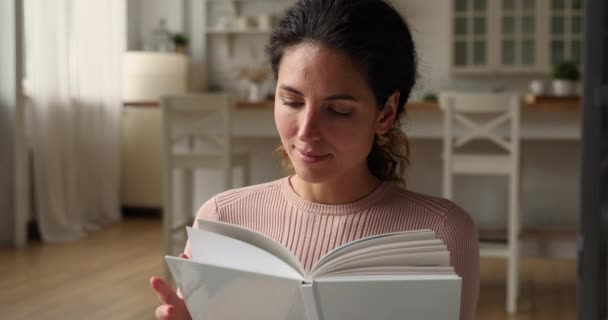 Drömmande ung kvinna läser en bok ensam hemma — Stockvideo