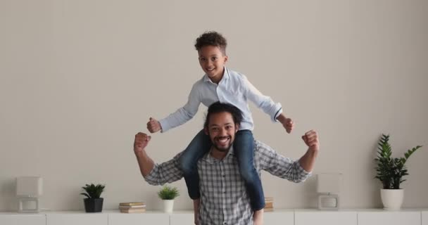 Little son sit on father shoulders smiling showing biceps — Stock Video