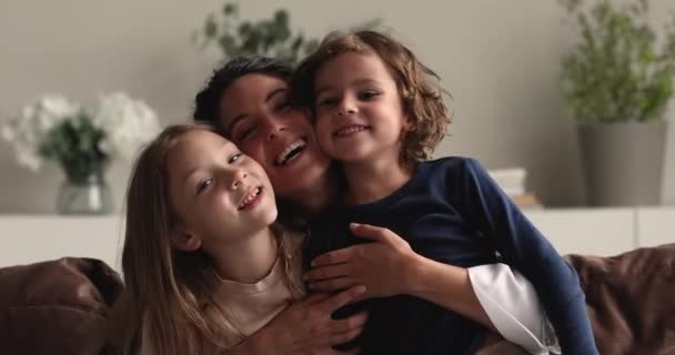 Mujer hispana joven sonriente abrazando a los pequeños niños preescolares hermanos. — Vídeos de Stock