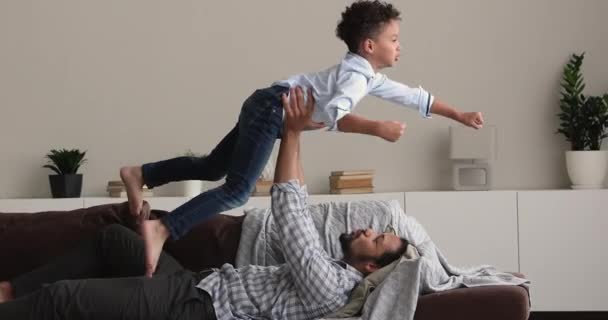 African dad lift son on arms play together at home — Stock Video