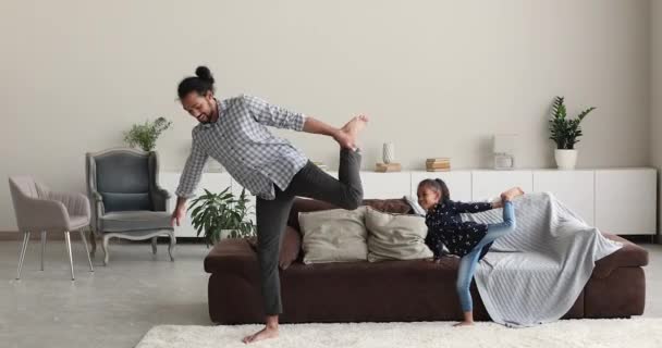 Afrikansk far och dotter utför balanserande motion i vardagsrummet — Stockvideo