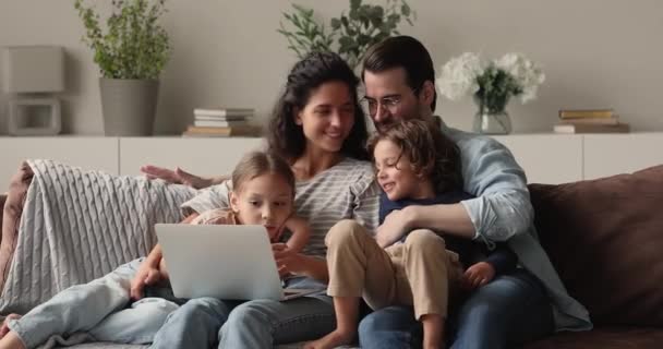 Χαμογελώντας στοργικό νεαρό οικογενειακό ζευγάρι χρησιμοποιώντας υπολογιστή με μικρά παιδιά. — Αρχείο Βίντεο