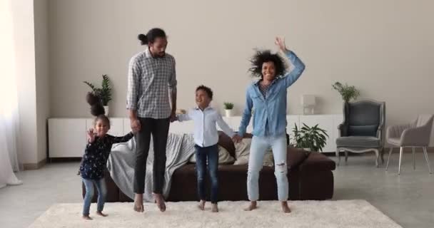 Szczęśliwa afrykańska rodzina z dziećmi trzymającymi się za ręce skaczące w środku — Wideo stockowe