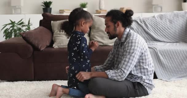 Afrikansk pappa sitter på golvet prata med lilla sötnos dotter — Stockvideo