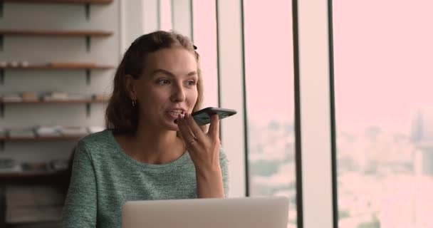 Молодая женщина держит современный смартфон говорить с помощью громкой связи — стоковое видео