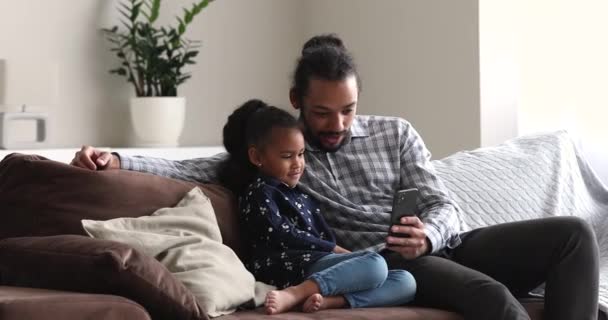 Baba ve kızı akıllı telefon kullanıyor. İnternetteki komik içeriği izliyorlar. — Stok video