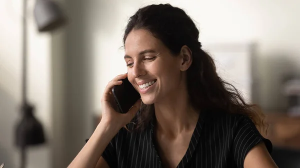 Jovem mulher envolvida em conversa telefônica segurando célula no ouvido — Fotografia de Stock