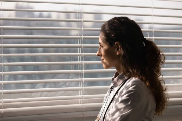 Joven terapeuta médica latina parada junto a la ventana con sonrisa — Foto de Stock