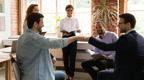 Excited employees giving fists bump, celebrating success at corporate meeting — Stock Photo, Image