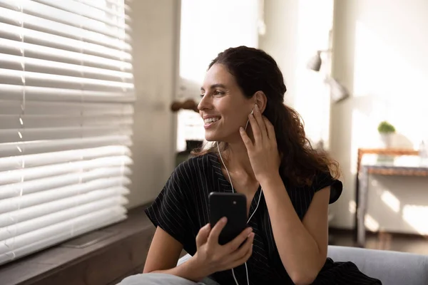 Jonge vrouw in headset ontspannen met telefoon kijken naar venster — Stockfoto