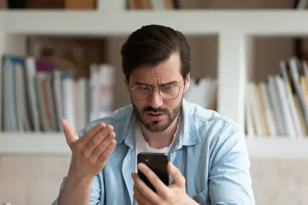 Закрыть несчастного человека в очках, смотрящего на экран телефона — стоковое фото
