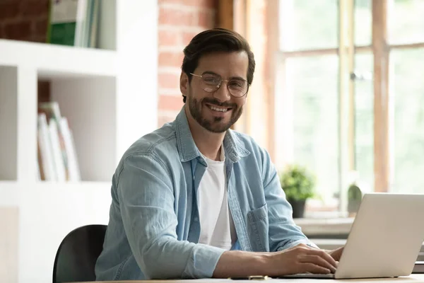 Huvudskott porträtt leende man i glasögon sitter vid skrivbordet — Stockfoto