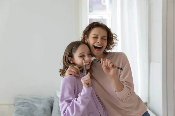 Crazy binda unga mor och tonåring dotter sjunga låtar. — Stockfoto