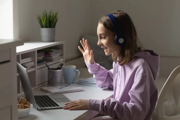 Gelukkig weinig vrouwelijke tiener in hoofdtelefoon starten video oproep. — Stockfoto