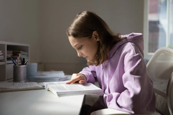 Adolescente joven concentrada leyendo libro de texto en casa. —  Fotos de Stock