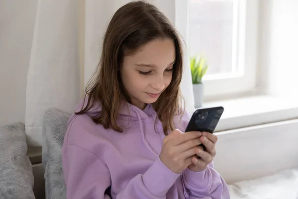 Зависимая от современных технологий молодая девушка-подросток с помощью смартфона. — стоковое фото
