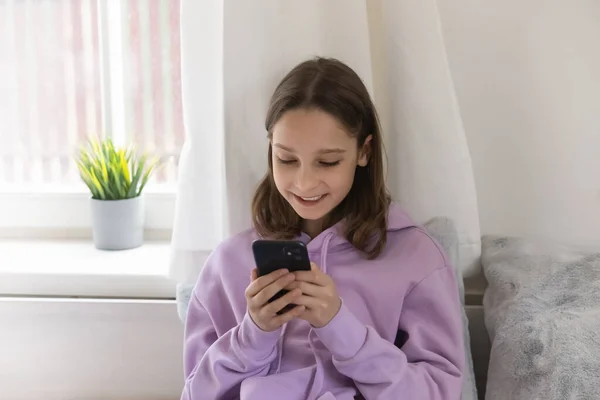 Счастливая девочка-подросток пользуется телефоном дома. — стоковое фото