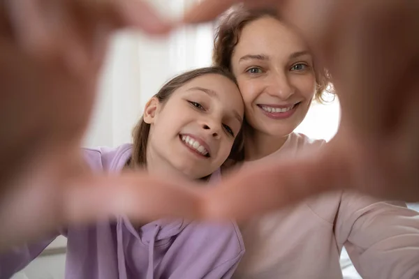 Close up teen girl showing heart sign with mother. — Stock Photo, Image