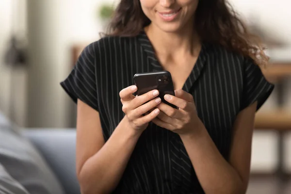 Молодая женщина держит смартфон с помощью мобильного приложения в помещении — стоковое фото