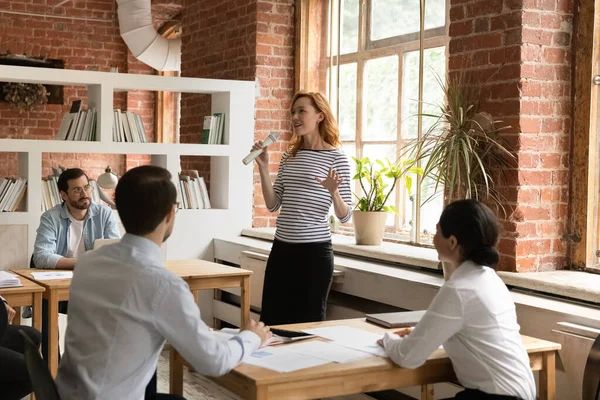 Selbstbewusste Geschäftsfrau hält Mikrofon in der Hand, leitet Briefing mit verschiedenen Mitarbeitern — Stockfoto
