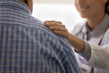 Bakım kliniği çalışanı endişeli hasta adamı rahatlatıyor. Hasta iyimserliğe ilham veriyor.