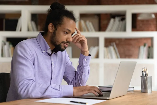 Focado pensativo empresário afro-americano olhando para a tela do laptop — Fotografia de Stock