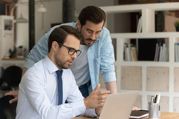 Zelfverzekerde mentor coach in stagiair brillentraining, wijzend naar scherm — Stockfoto