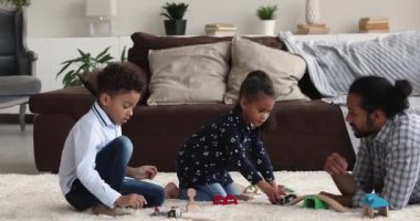 Afrikalı baba ve çocuklar evde demiryolu oynuyorlar.