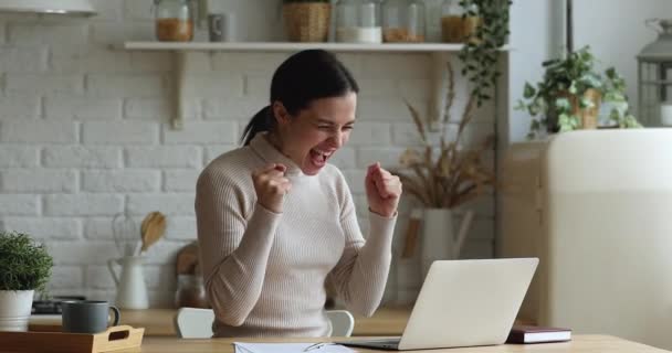 Frau liest E-Mail auf Laptop und freut sich über gute Nachrichten — Stockvideo