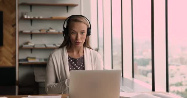 Mujer de negocios usar auriculares llevar las negociaciones al cliente por videoconferencia — Vídeos de Stock