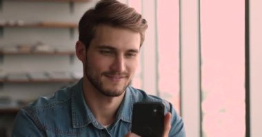 Çekici milenyum insanı akıllı telefon modern cihazıyla kapalı bir yerde oturur.