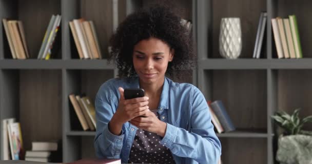 Африканская женщина держит смартфон чтение отличные смс новости чувствует себя счастливым — стоковое видео
