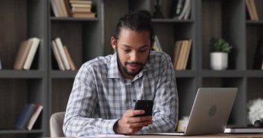 Afrikalı adam akıllı telefon kullanarak masada oturup mesajlarını paylaşıyor.