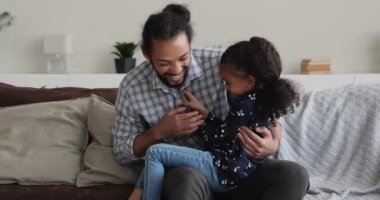 Afrikalı kız ve baba birbirlerini gıdıklayıp gülüyorlar.