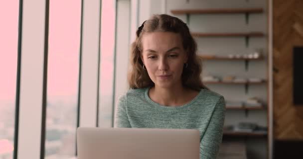 Pensive vrouwelijke werknemer zitten op de werkplek werken op laptop — Stockvideo