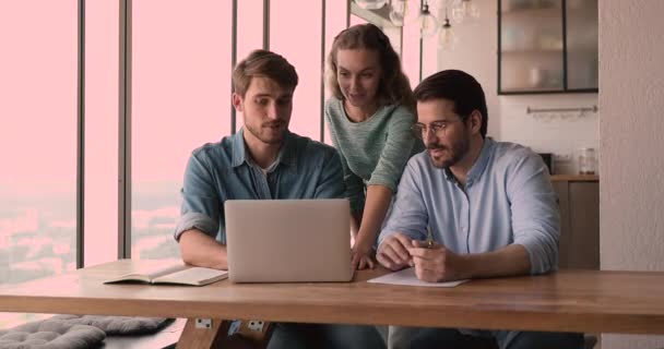 Três colegas trabalham juntos no laptop de uso do projeto — Vídeo de Stock