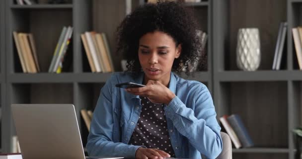 Afrikaanse vrouw zitten op de werkplek chatten met collega op speakerphone — Stockvideo